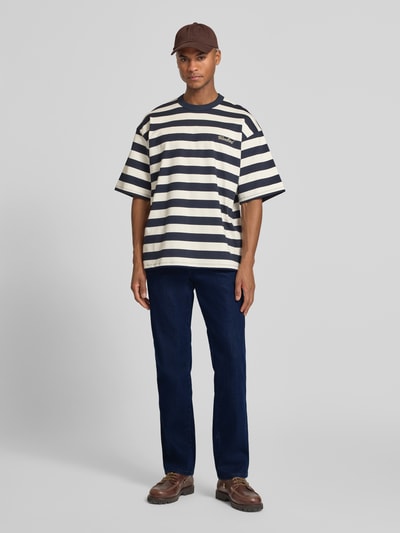 Männermodel trägt Straight Fit Jeans im 5-Pocket-Design Modell 'Texas' von Wrangler, Dunkelblau, Baumwoll-Mix mit Stretch-Anteil, Gerader-Schnitt, Knopf-Reißverschluss, Herren Jeans, Ganzkörperansicht von vorne.