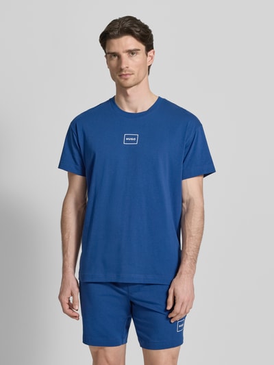 Männermodel trägt Regular Fit T-Shirt aus Baumwoll-Mix Modell 'LAZE T-SHIRT' von HUGO in Optik: Unifarben mit Label-Print, Rundhals, Kurzarm, Herren T-Shirt, Ganzkörperansicht von vorne.