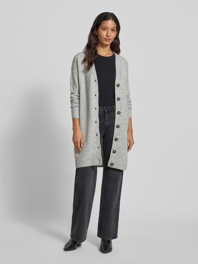 Frauenmodel trägt Relaxed Fit Cardigan mit Woll-Anteil von Christian Berg Woman in Hellgrau, grobe Strickstruktur, Knopfleiste, Ganzkörperansicht von vorne.
