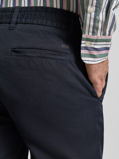 Männermodel trägt Tapered Chinoshorts aus Baumwoll-Mix von BOSS Orange, Optik: Unifarben, Label-Patch, Twill, Nahaufnahme Oberkörper von hinten.