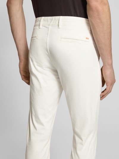 Männermodel draagt Slim Fit Chino aus Baumwoll-Mix Modell 'Chino Slim' van BOSS Orange, effen kleuren, labelpatch, twill, Ganzkörperansicht Rückansicht.
