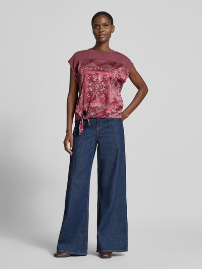 Frauenmodel trägt Blusenshirt mit Knotendetail von Christian Berg Woman Selection aus Satin in Regular-Fit mit Rundhalsausschnitt, Ganzkörperansicht von vorne. Rückenlänge bei Größe 36: 52 cm.