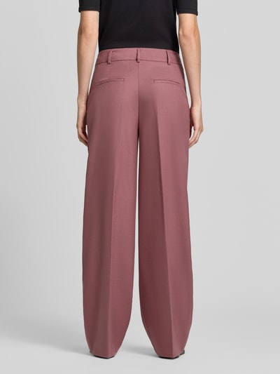 Modelka nosi spodnie Wide Fit Hose mit Viskose-Anteil od Christian Berg Woman Selection w różowym kolorze, mieszanka materiałów z dodatkiem wiskozy, Kanty, zapięcie na haftkę i zamek błyskawiczny, szerokość w rozmiarze 36: 46 cm, długość wewnętrzna nogawki w rozmiarze 36: 85 cm, widok całej sylwetki od tyłu.