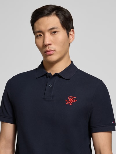 Männermodel trägt Regular Fit Poloshirt aus reiner Baumwolle von Tommy Hilfiger in Optik: Unifarben mit Logo-Stitching, Nahaufnahme Oberkörper.