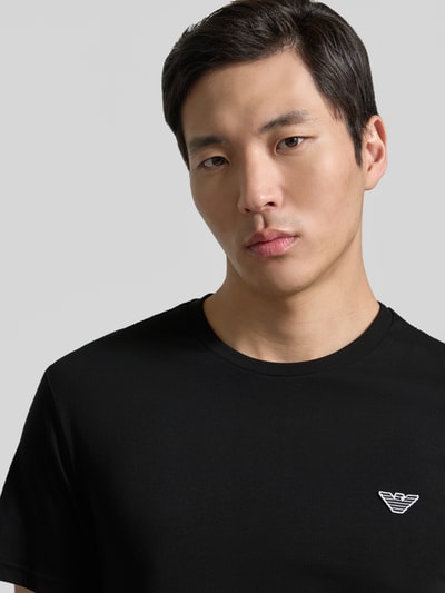 Männermodel trägt T-Shirt mit Logo-Patch und Rundhalsausschnitt von Emporio Armani, Schwarz, Reine Baumwolle, Modern Fit, Nahaufnahme Oberkörper