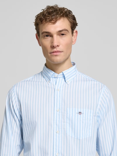 Männermodel trägt Slim Fit Freizeithemd mit Brusttasche von Gant, hellblau-weiß gestreift, reine Baumwolle, Nahaufnahme Oberkörper.