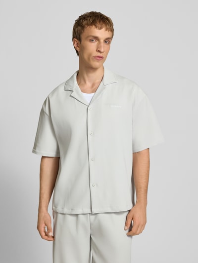 Männermodel trägt Relaxed Fit Freizeithemd mit Reverskragen Modell 'Troy' von Pegador in hellem Beige mit Strukturmuster, Logo-Stitching, kurzärmeligem Design und durchgehender Knopfleiste, Ganzkörperansicht von vorne.