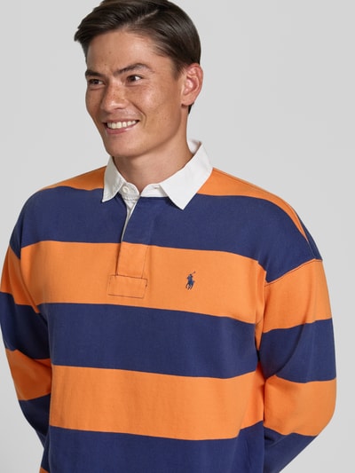 Mannenmodel draagt oversized pullover uit pure katoen model '6/1' van Polo Ralph Lauren, Heren pullover, blauw-oranje strepen, detailopname bovenlichaam.