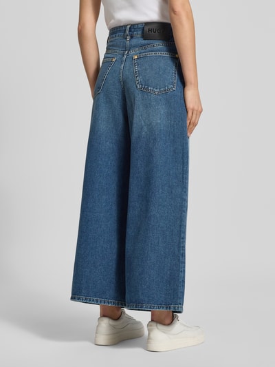 Frauenmodel trägt Regular Fit Wide Leg Jeans aus reiner Baumwolle Modell 'Geredith' von HUGO in Blau, High Waist, 5-Pocket, Ganzkörperansicht Rückansicht.