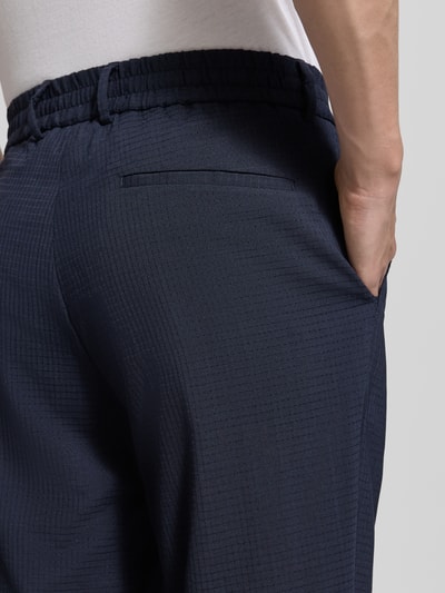 Männermodel trägt Slim Fit Hose aus Woll-Mix Modell 'P-GENIUS' von BOSS, efekt: wzór w kratkę, półprzezroczysty efekt, wpuszczana kieszeń, krój slim fit, mieszanka wełny, kolor granatowy, Ganzkörperansicht Rückansicht, zbliżenie na biodra
