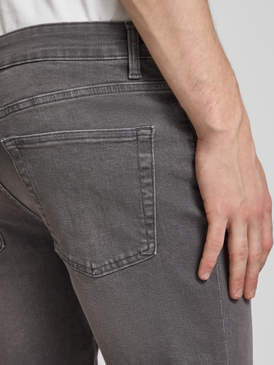 Männermodel trägt Regular Fit Bermudas aus Baumwoll-Mix mit Viskose-Anteil Modell 'PLY' von Only & Sons in grauer Denim-Optik, Detailaufnahme. 5-Pocket-Design, Label-Patch, Twill-Materialverarbeitung.