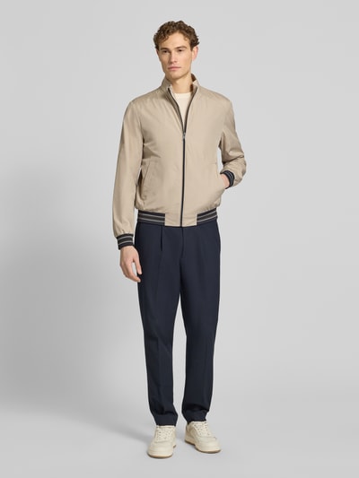 Männermodel trägt Blouson mit Stehkragen und Reißverschluss von Geox in Beige, kombiniert mit Eingrifftaschen, Regular-Fit, Ganzkörperansicht von vorne. Rückenlänge 68 cm, Schulterbreite 46 cm, Brustweite 56 cm, Ärmellänge 68 cm, Größe M.