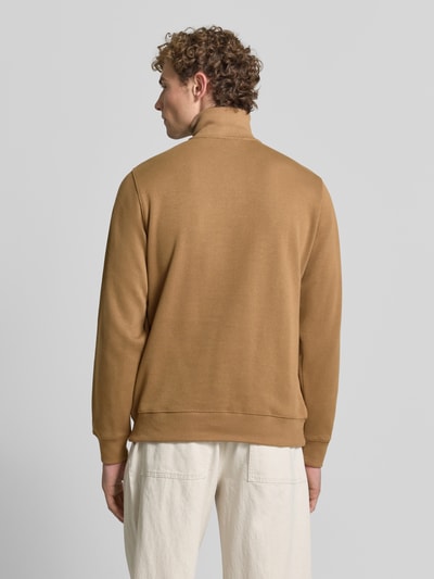 Männermodel trägt Regular Fit Troyer aus reiner Baumwolle von Lacoste in Braun, weiße Hose, glatte Struktur, Ganzkörperansicht Rückansicht. Herren Troyer von Lacoste.