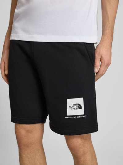 Männermodel trägt schwarze Regular Fit Shorts mit Eingrifftaschen von The North Face aus Baumwoll-Mix, Nahaufnahme Oberschenkel. Bundweite bei Größe M: 40 cm, Innenbeinlänge bei Größe M: 18 cm.