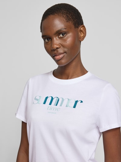 Frauenmodel trägt Regular Fit T-Shirt aus reiner Baumwolle von Tom Tailor in Weiß mit Statement Print, Jersey-Textur, Nahaufnahme Oberkörper.