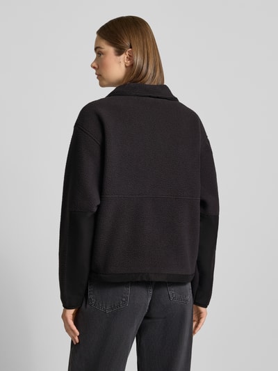 Frauenmodel trägt Regular Fit Fleecejacke mit Stehkragen Modell 'YUMIORI' von The North Face, schwarze Farbe, weiche Textur, Ganzkörperansicht Rückansicht. Damen Fleecejacke aus Fleece mit Logo-Stitching, Reißverschluss, Rückenlänge 58 cm, Schulterbreite 52 cm, Brustweite 58 cm, Ärmellänge 57 cm.