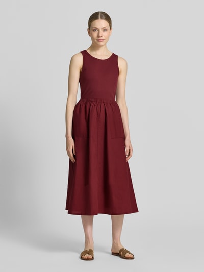 Frauenmodel trägt Fit and Flare Freizeitkleid aus reiner Baumwolle von s.Oliver RED LABEL in Dunkelrot mit glatter Struktur, Ganzkörperansicht von vorne.