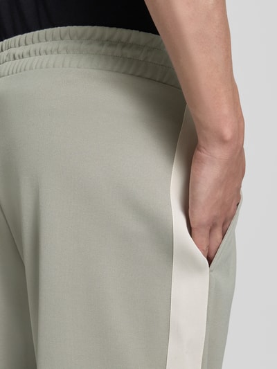Männermodel trägt Regular Fit Jogpants mit Baumwoll-Anteil Modell 'DOLOS' von HUGO, Optik: Unifarben, Kontraststreifen, Materialverarbeitung: Sweat, Nahaufnahme Oberkörper.