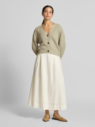 Modelka kobieca ma na sobie kardigan rozpinany o kroju oversized z dekoltem w serek model 'LEA' od VERO MODA, jasnobeżowy, faktura prążkowana; widok całej sylwetki z przodu.