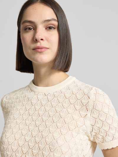 Modelka nosi Strickshirt mit Lochstickerei von Jake*s Collection, kremowy bawełniany materiał z ażurowym wzorem, półrękaw, krój prosty, dekolt okrągły, zbliżenie na górną część ciała.