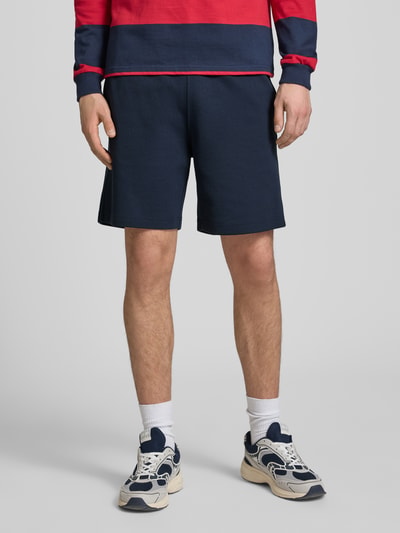 Männermodel trägt Shorts mit elastischem Bund und Label-Stitching von CHAMPION, navyblau, Baumwoll-Mix, Regular Fit, Ganzkörperansicht von vorne.