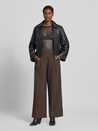Kobieta nosi bluzkę z długim rękawem z okrągłym dekoltem, model 'LOVA' od VERO MODA, przezroczysta czarna tkanina, krój slim fit, całkowity widok z przodu.