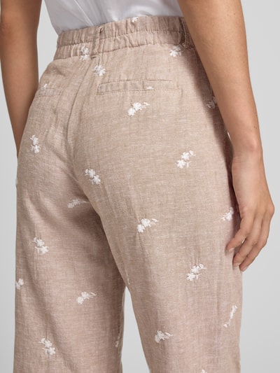 Frauenmodel trägt Hose aus Leinen-Baumwoll-Mix mit Stitchings von Christian Berg Woman in Beige mit weißen Blumen, verkürzte Passform, Nahaufnahme Rückansicht.
