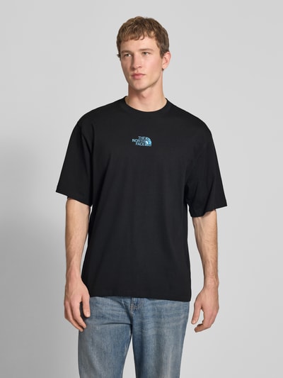 Męski model nosi Oversized T-Shirt mit Logo und Rundhalsausschnitt von The North Face, czarny kolor, bawełna, logo z przodu, długość tyłu w rozmiarze M: 73 cm, Ganzkörperansicht von vorne.