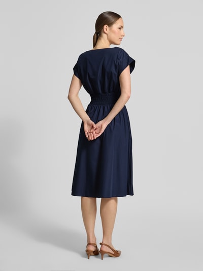 Frauenmodel trägt Knielanges Kleid mit Rundhalsausschnitt von Christian Berg Woman Selection in Dunkelblau mit Kappärmel, Material-Mix mit Baumwoll-Anteil, Taillierter Schnitt, Elastisches Taillenband, Rückenlänge 110 cm bei Größe 36, Ganzkörperansicht Rückansicht.