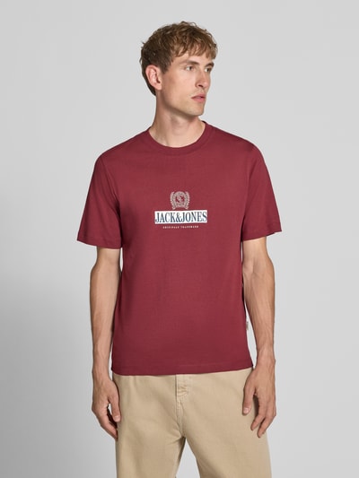 Męski model nosi t-shirt z nadrukiem z logo T-shirt mit Label-Print Modell 'FREDERIKSBERG' od JACK & JONES, bawełna, prosty krój, okrągły dekolt, długość tyłu w rozmiarze M: 70 cm, całkowity widok z przodu