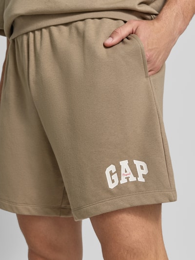 Männermodel trägt Straight Fit Shorts mit Logo-Stitching Modell 'Arch' von GAP, beigefarbener Baumwoll-Mix, Nahaufnahme Oberschenkel.