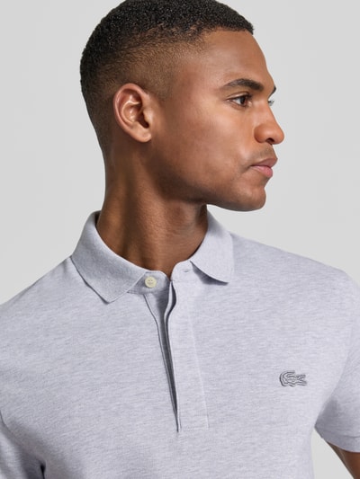 Męski model nosi Regular Fit Poloshirt aus Baumwoll-Mix von Lacoste, efekt: jednolity kolor, wyhaftowane logo, mieszanka bawełny, pika, kołnierzyk polo, krótki rękaw, prążkowane zakończenie rękawów, widok na górną część tułowia z przodu