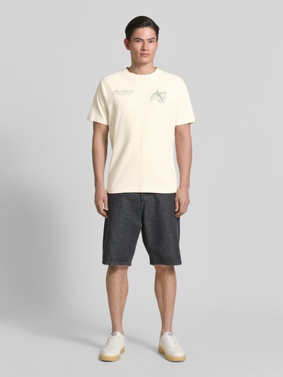 Męski model nosi Relaxed Fit T-Shirt mit Label-Prints und Rundhalsausschnitt von PME Legend z bawełny, kolor kremowy, nadruki z logo, krój relaxed fit, długość tyłu w rozmiarze M: 70 cm, Ganzkörperansicht von vorne.