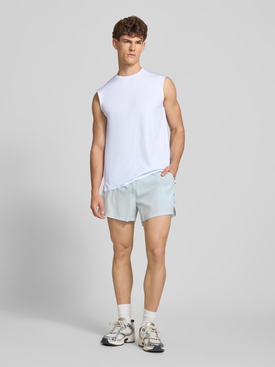 Mężczyzna model nosi Relaxed Fit Top mit Logo-Print Modell 'OLIOS' od Ellesse, biały, okrągły dekolt, elastyczna tkanina, długość tyłu w rozmiarze M: 74 cm, Ganzkörperansicht von vorne.