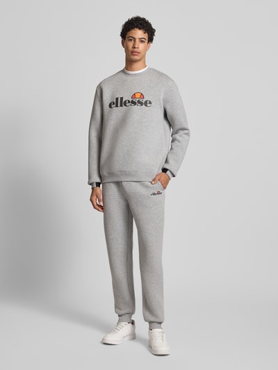 Männermodel trägt Sweatpants mit Logo Modell 'SIRTORI' von ellesse, grau, Material-Mix mit Viskose-Anteil, elastischer Bund, Regular-Fit, Herren; Ganzkörperansicht von vorne.