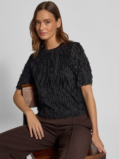 Vrouwenmodel draagt T-shirt met Rüschenbesatz van Jake*s Collection, materiaalmix met stretch, recht model, ronde hals, halve mouw, ruglengte maat S 50 cm, effen zwart met structuur, voorkant bovenlichaam close-up.