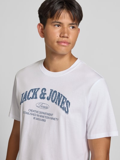 Männermodel trägt Regular Fit T-Shirt aus reiner Baumwolle Modell 'Denver' von JACK & JONES in Weiß mit Logo-Print, Nahaufnahme Oberkörper. Herren T-Shirt, Rückenlänge bei Größe M 69 cm.