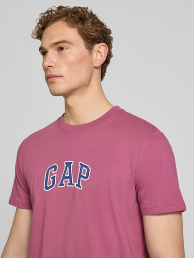 Männermodel trägt T-Shirt mit Logo-Patch und Rundhalsausschnitt von GAP in Pink, reine Baumwolle, Straight Fit, Nahaufnahme Oberkörper.