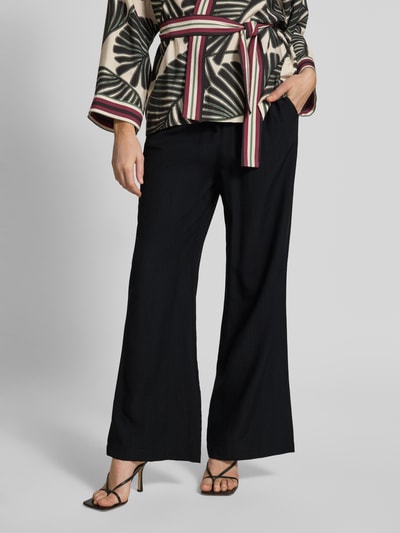 Frauenmodel trägt Flared Fit Stoffhose aus Viskose-Mix von Christian Berg Woman Selection, Damen Stoffhose mit elastischem Bund und Tunnelzug, strukturierte schwarze Oberfläche, Ganzkörperansicht von vorne.