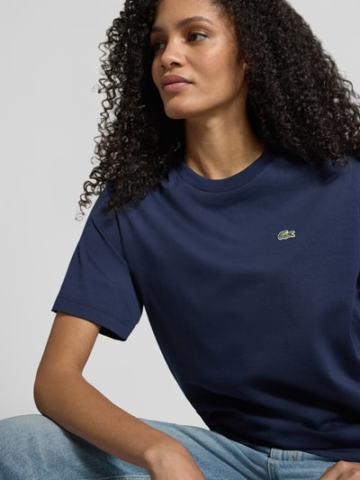 Modelka nosi Relaxed Fit T-Shirt aus reiner Baumwolle od Lacoste Sport, granatowy kolor, logo z przodu, krótki rękaw, bawełna, zbliżenie górnej części ciała.