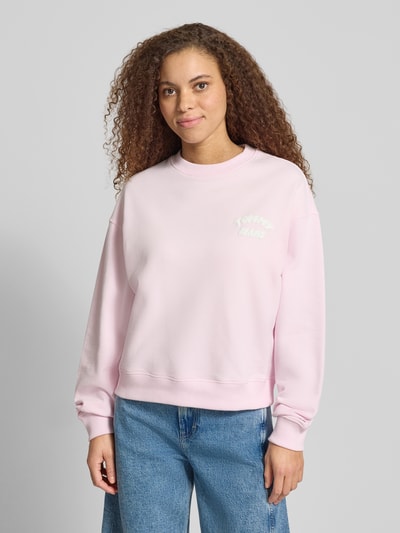 Frauenmodel trägt Boxy Fit Sweatshirt aus reiner Baumwolle von Tommy Jeans in Optik: Unifarben mit Label-Print, Materialverarbeitung: Sweat, Ganzkörperansicht von vorne.