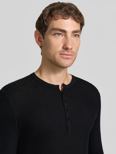 Männermodel trägt Strickpullover aus Lyocell-Woll-Mix mit Knopfleiste von Antony Morato, schwarze Ripp-Optik, Nahaufnahme Oberkörper, Slim Fit.
