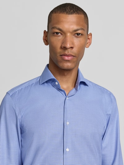 Männermodel trägt blau-weiß gemustertes Slim-Fit Businesshemd aus Baumwolle Modell 'H-HANK-Sp-B1-C1-263' von BOSS, Nahaufnahme Oberkörper. Herren Businesshemd von BOSS.
