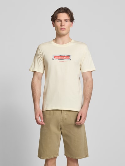 Männermodel trägt T-Shirt mit Logo und Rundhalsausschnitt von Jack & Jones in Beige, reine Baumwolle, Regular Fit, Ganzkörperansicht von vorne.