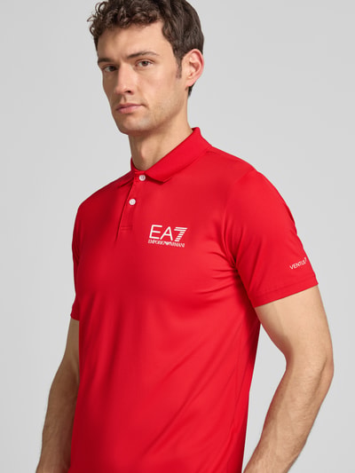 Männermodel trägt Regular Fit Poloshirt mit Logo von EA7 Emporio Armani in Rot mit Knopfleiste, Material-Mix, Nahaufnahme Oberkörper.