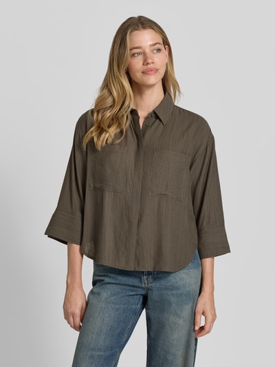 Frauenmodel trägt Regular Fit Bluse aus Viskose-Mix mit 3/4-Arm Modell 'Forna' von OPUS in Khaki, sichtbare Textur, Hemdblusenkragen, verdeckte Knopfleiste und Brusttaschen, Ganzkörperansicht von vorne, Rückenlänge bei Größe 36: 64 cm, Ärmellänge: 40 cm.