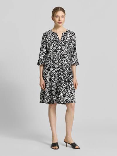 Frauenmodel trägt Minikleid mit Tunika-Ausschnitt von Christian Berg Woman Selection, Reine Baumwolle, Taillierte Passform, Halbarm, Schwarz-Weiß Muster, Ganzkörperansicht von vorne. Rückenlänge bei Größe 36: 89 cm, Brustweite: 41 cm, Ärmellänge: 43 cm.