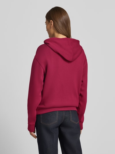 Frauenmodel trägt Hoodie aus Viskose-Mix mit Logo Modell 'IMA' von MSCH Copenhagen in Dunkelrot, weiche Struktur, Ganzkörperansicht Rückansicht.