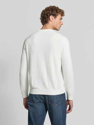 Männermodel trägt Regular Fit Pullover aus Baumwoll-Mix von Lacoste in Weiß mit glatter Textur und blauen Jeans, Ganzkörperansicht Rückansicht.