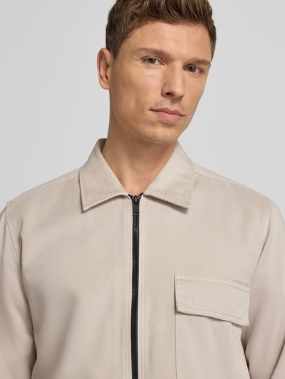 Męski model nosi Regular Fit Hemdjacke aus reiner Baumwolle Modell 'M_LORUM' od BOSS Orange w jednolitym beżowym kolorze, z kołnierzem klasycznym, długimi rękawami i kieszenią na piersi; zbliżenie na górną część ciała.